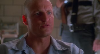 Movie still from “Natural Born Killers” (1994), directed by Oliver Stone – A man with a shaved head and a blue shirt; Close Up shot, Low angle