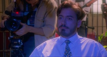 Movie still from “Natural Born Killers” (1994), directed by Oliver Stone – A person sitting in front of a camera; Close Up shot, High angle