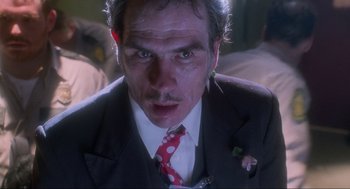 Movie still from “Natural Born Killers” (1994), directed by Oliver Stone – A person wearing a suit and tie; Close Up shot, Low angle