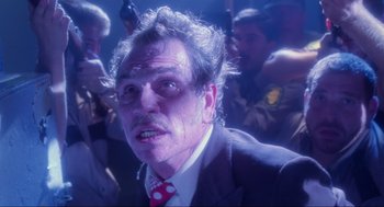 Movie still from “Natural Born Killers” (1994), directed by Oliver Stone – A person wearing a suit and tie; Close Up shot, Low angle