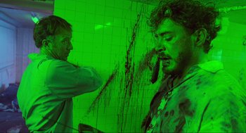 Movie still from “Natural Born Killers” (1994), directed by Oliver Stone – Two men in a green room one is brushing his teeth; Medium shot, Over the shoulder angle