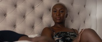 Movie still from “Needle in a Timestack” (2021), directed by John Ridley – A woman sitting on top of a bed in front of a white wall; Close Up shot, Over the shoulder angle