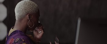 Movie still from “Needle in a Timestack” (2021), directed by John Ridley – A woman smoking a cigarette while holding a cell phone to her ear; Close Up shot, Low angle