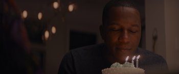Movie still from “Needle in a Timestack” (2021), directed by John Ridley – A man is blowing out a candle on a cake; Close Up shot, Over the shoulder angle