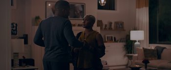 Movie still from “Needle in a Timestack” (2021), directed by John Ridley – A man and a woman shaking hands in a living room; Medium shot, Over the shoulder angle