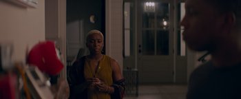 Movie still from “Needle in a Timestack” (2021), directed by John Ridley – A woman standing in front of a door looking down; Medium shot, Over the shoulder angle