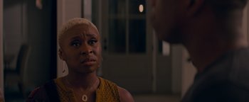 Movie still from “Needle in a Timestack” (2021), directed by John Ridley – A woman in a yellow shirt is looking at the camera; Close Up shot, Over the shoulder angle