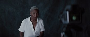 Movie still from “Needle in a Timestack” (2021), directed by John Ridley – A woman in a white shirt is looking down; Medium shot, Low angle