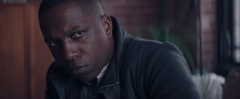 Movie still from “Needle in a Timestack” (2021), directed by John Ridley – A person wearing a black jacket; Close Up shot, Low angle