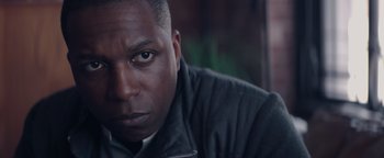 Movie still from “Needle in a Timestack” (2021), directed by John Ridley – A man's face in a black jacket; Close Up shot, Low angle