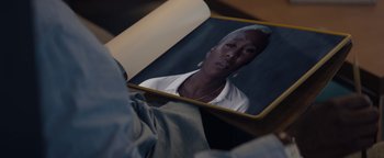 Movie still from “Needle in a Timestack” (2021), directed by John Ridley – A person is looking at a picture of an older woman; Extreme Close Up shot, High angle