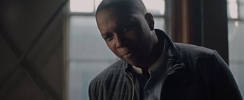 Movie still from “Needle in a Timestack” (2021), directed by John Ridley – A person wearing a jacket looking at the camera; Close Up shot, Low angle