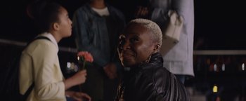 Movie still from “Needle in a Timestack” (2021), directed by John Ridley – A woman in a leather jacket holding a flower; Close Up shot, Over the shoulder angle