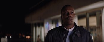 Movie still from “Needle in a Timestack” (2021), directed by John Ridley – A person wearing a jacket and looking at the camera; Close Up shot, Low angle