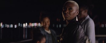 Movie still from “Needle in a Timestack” (2021), directed by John Ridley – A woman standing in front of a group of people; Close Up shot, Low angle