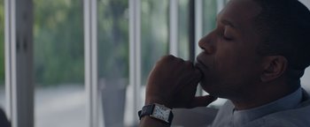 Movie still from “Needle in a Timestack” (2021), directed by John Ridley – A person with a watch is sitting in front of a window; Close Up shot, Low angle