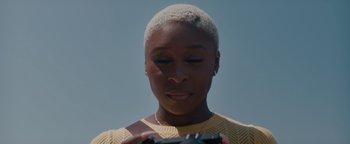 Movie still from “Needle in a Timestack” (2021), directed by John Ridley – A woman is looking at her cell phone while standing outside; Close Up shot, Low angle