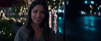 Movie still from “Needle in a Timestack” (2021), directed by John Ridley – A woman smiling for the camera in front of lights; Close Up shot, Over the shoulder angle
