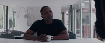 Movie still from “Needle in a Timestack” (2021), directed by John Ridley – A man sitting at a table holding a coffee cup; Close Up shot, Low angle
