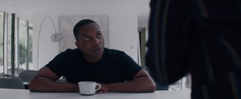 Movie still from “Needle in a Timestack” (2021), directed by John Ridley – A man sitting at a table holding a coffee cup; Close Up shot, Over the shoulder angle