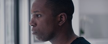 Movie still from “Needle in a Timestack” (2021), directed by John Ridley – A man's face in a black shirt; Close Up shot, Low angle