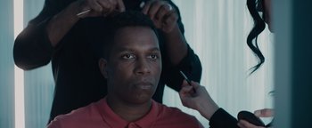 Movie still from “Needle in a Timestack” (2021), directed by John Ridley – A man getting his hair combed by a stylist; Close Up shot, Over the shoulder angle