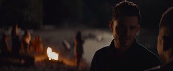 Movie still from “Needle in a Timestack” (2021), directed by John Ridley – A man standing in front of a fire at night; Close Up shot, Over the shoulder angle