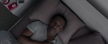 Movie still from “Needle in a Timestack” (2021), directed by John Ridley – A man laying in a bed with a pillow on top; Close Up shot, Overhead angle