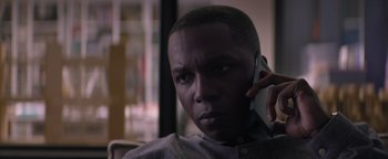 Movie still from “Needle in a Timestack” (2021), directed by John Ridley – A man holding a cell phone up to his ear; Close Up shot, Low angle