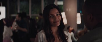Movie still from “Needle in a Timestack” (2021), directed by John Ridley – A woman with long dark brown hair smiles for the camera; Close Up shot, Over the shoulder angle