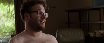 Movie still from “Neighbors” (2014), directed by Nicholas Stoller – A man with glasses is sitting on a couch; Close Up shot, Over the shoulder angle