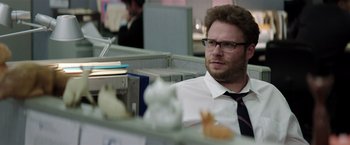 Movie still from “Neighbors” (2014), directed by Nicholas Stoller – A man sitting at a desk in an office setting; Medium shot, Over the shoulder angle