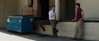 Movie still from “Neighbors” (2014), directed by Nicholas Stoller – A man standing on the side of the street holding a cup; Wide shot, Over the shoulder angle