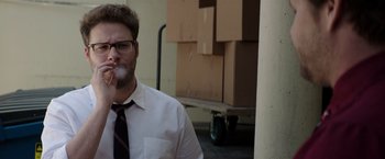 Movie still from “Neighbors” (2014), directed by Nicholas Stoller – A man smoking a cigarette while standing next to boxes; Medium shot, Over the shoulder angle