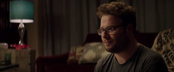 Movie still from “Neighbors” (2014), directed by Nicholas Stoller – A person wearing glasses sitting on a couch; Close Up shot, Over the shoulder angle