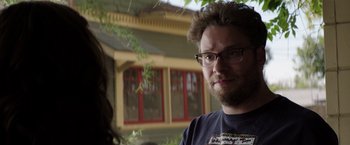 Movie still from “Neighbors” (2014), directed by Nicholas Stoller – A person wearing glasses with a building in the background; Close Up shot, Over the shoulder angle