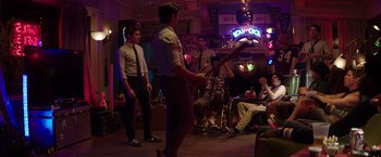Movie still from “Neighbors” (2014), directed by Nicholas Stoller – A group of men in a room with a guitar; Wide shot, Over the shoulder angle