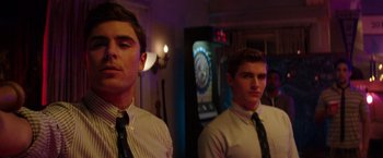 Movie still from “Neighbors” (2014), directed by Nicholas Stoller – Two young men standing next to each other in a room; Medium shot, Over the shoulder angle