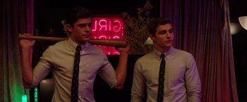 Movie still from “Neighbors” (2014), directed by Nicholas Stoller – Two young men in dress shirts and ties holding a hot dog in their mouth; Medium shot, Over the shoulder angle