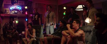Movie still from “Neighbors” (2014), directed by Nicholas Stoller – A group of men sitting in a living room watching tv; Medium shot, High angle
