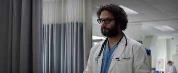 Movie still from “Neighbors” (2014), directed by Nicholas Stoller – A male doctor wearing a white lab coat and stethoscope; Medium shot, Low angle