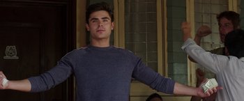 Movie still from “Neighbors” (2014), directed by Nicholas Stoller – A man standing in front of a building with his arms outstreched; Medium shot, Low angle