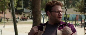 Movie still from “Neighbors” (2014), directed by Nicholas Stoller – A man with glasses is on a swing in a park; Close Up shot, Over the shoulder angle
