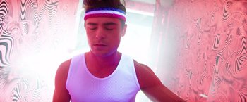 Movie still from “Neighbors” (2014), directed by Nicholas Stoller – A young man wearing a colorful headband is meditating; Close Up shot, Low angle
