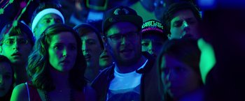 Movie still from “Neighbors” (2014), directed by Nicholas Stoller – A group of people in a room with neon lights; Close Up shot, Over the shoulder angle
