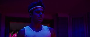Movie still from “Neighbors” (2014), directed by Nicholas Stoller – A young man wearing a white tank top and a headband; Close Up shot, Low angle