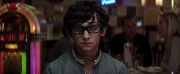 Movie still from “Neighbors” (2014), directed by Nicholas Stoller – A young man wearing glasses and a gray jacket; Close Up shot, Over the shoulder angle