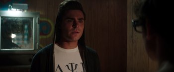 Movie still from “Neighbors” (2014), directed by Nicholas Stoller – A young man in white shirt and black jacket looking at the camera; Close Up shot, Over the shoulder angle