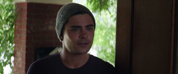 Movie still from “Neighbors” (2014), directed by Nicholas Stoller – A young man wearing a gray hat looking at the camera; Close Up shot, Over the shoulder angle