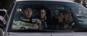 Movie still from “Neighbors” (2014), directed by Nicholas Stoller – A group of people in the back of a car looking at a cell phone; Medium shot, Over the shoulder angle